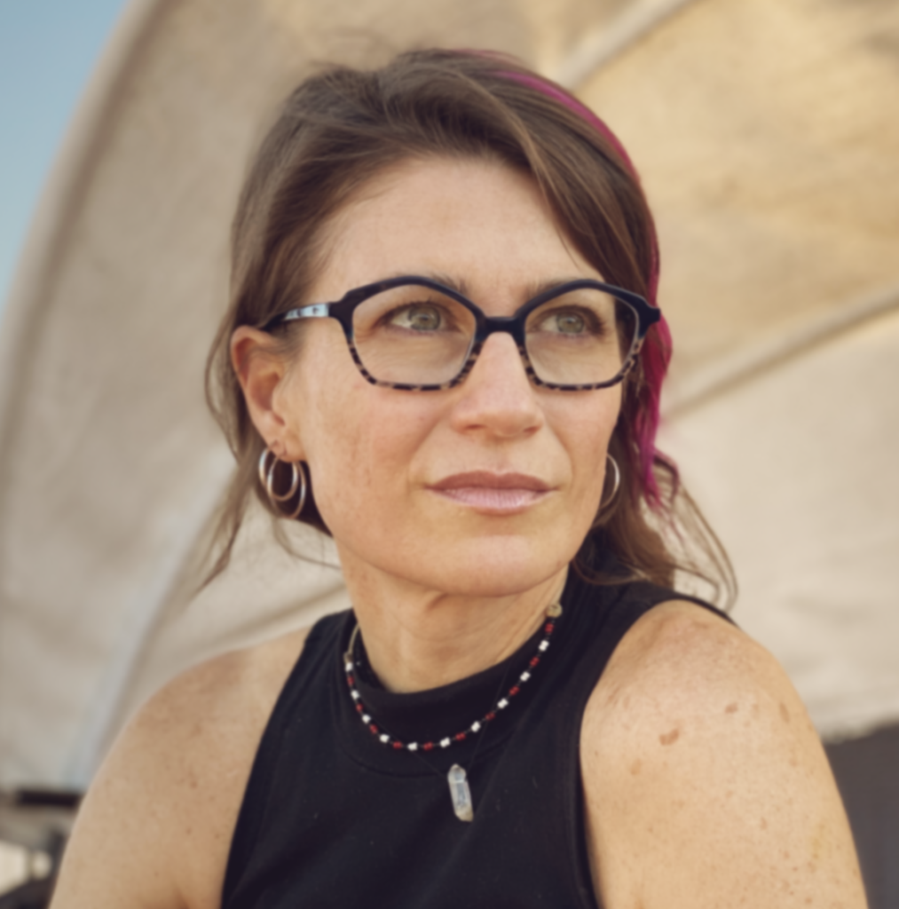 Headshot of Nancy Baker Cahill, a white woman wearing dark rimmed glasses and a black tank top