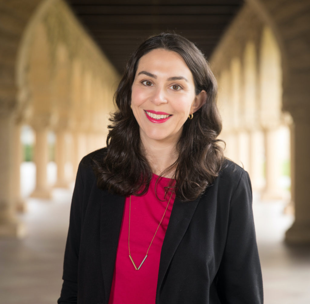 Laura Hertzfeld - white woman with dark brown hair, red shit, and black blazer