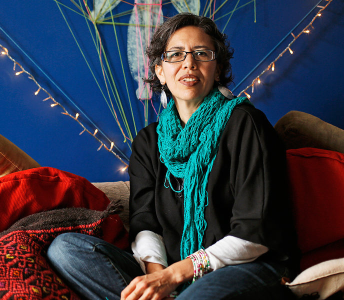 Blanka Amezkua seated in front of a royal blue wall