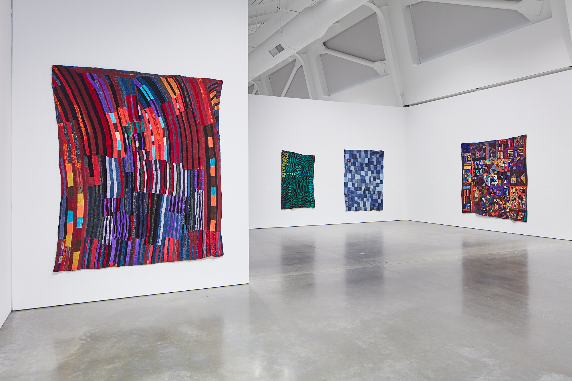 Interior shot of the exhibition, 4 quilts are visible hanging on the white walls