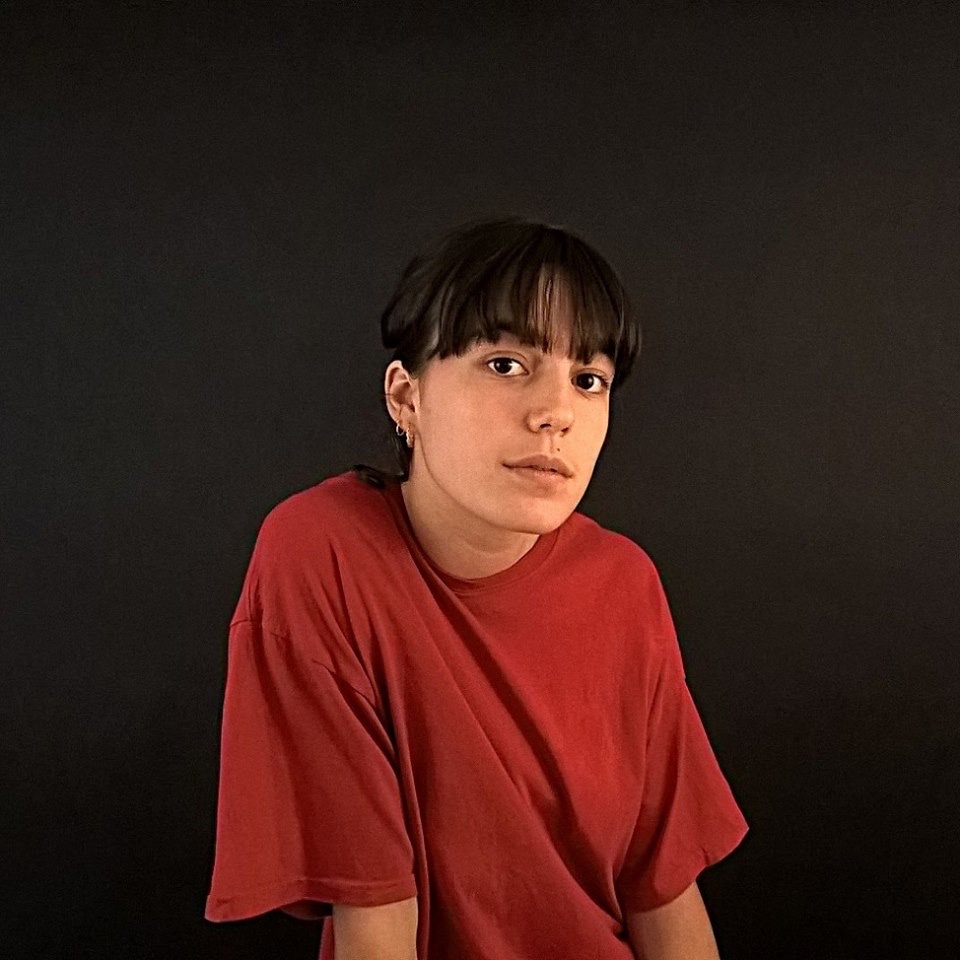 Philo Cohen seated against a black background wearing a red T-shirt