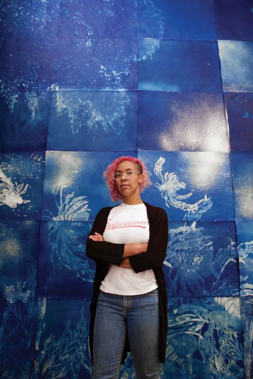 Andrea Chung standing in front of her artwork
