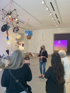 A woman speaks to a small group inside an art museum.