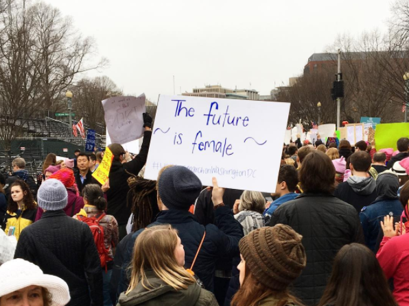 A photo of a crowd taken from the back with someone holding a sign that says "the future is female"