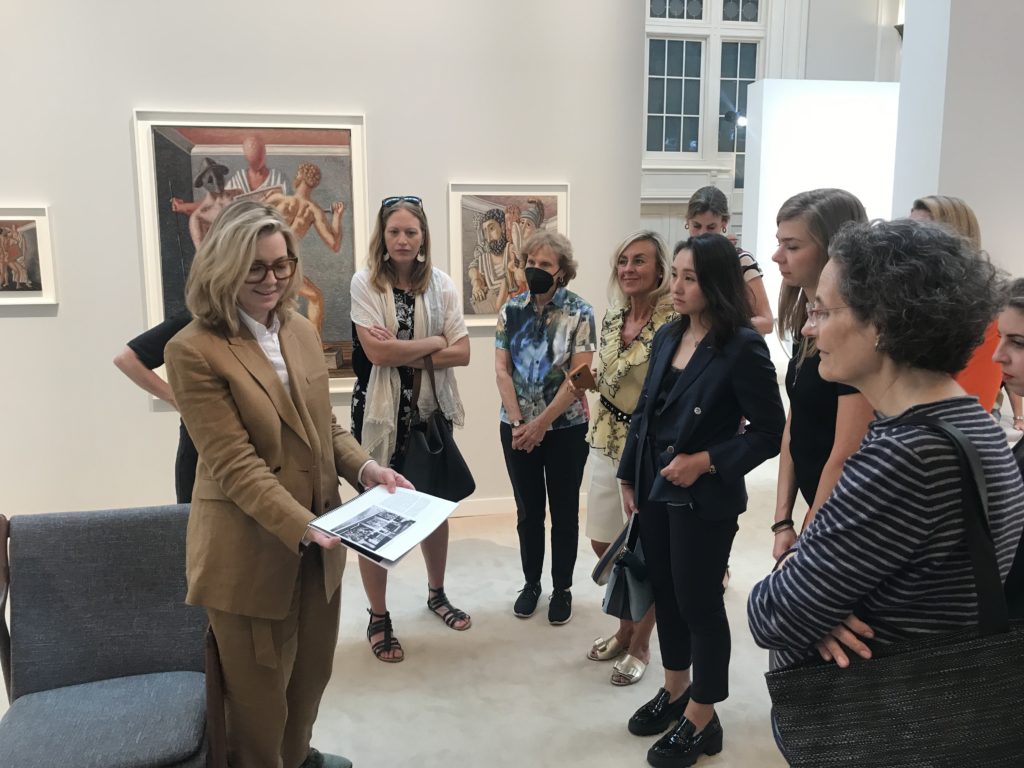 Independent director Elizabeth Dee shows a tour group an art book while standing inside a booth at the fair.