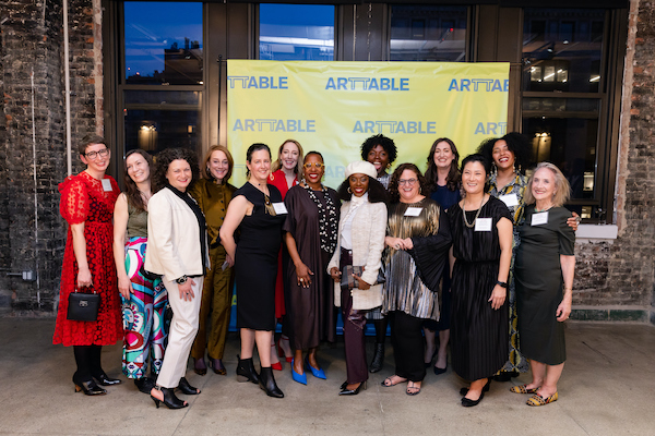 Group of women pose in front of an ArtTable sign.