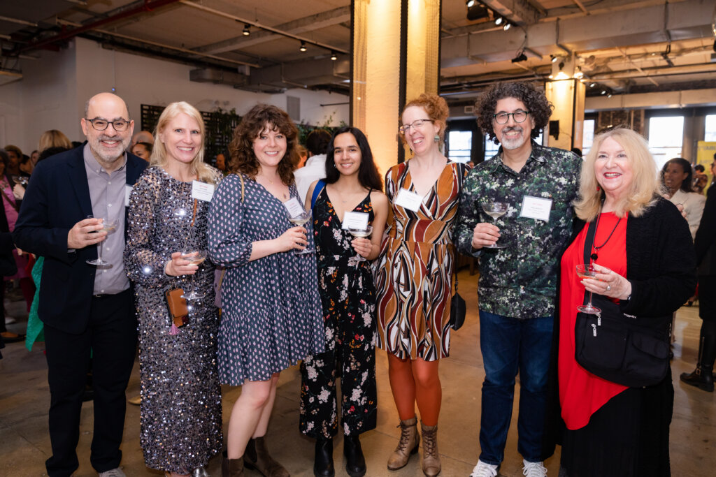 Seven people standing and holding drinks.