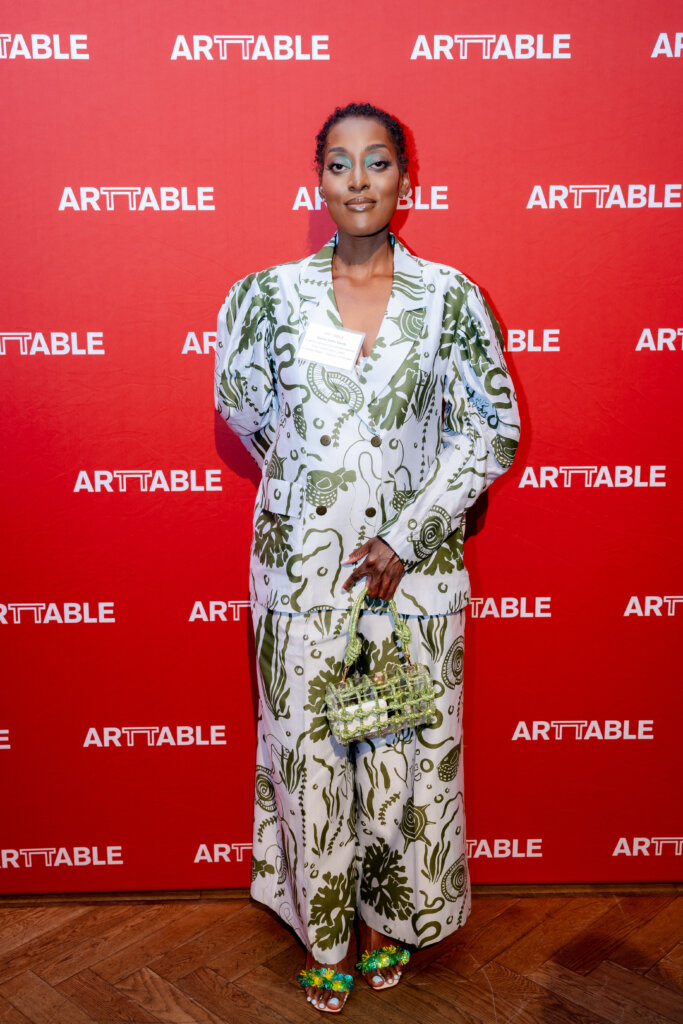 A woman standing in front of a red ArtTable banner