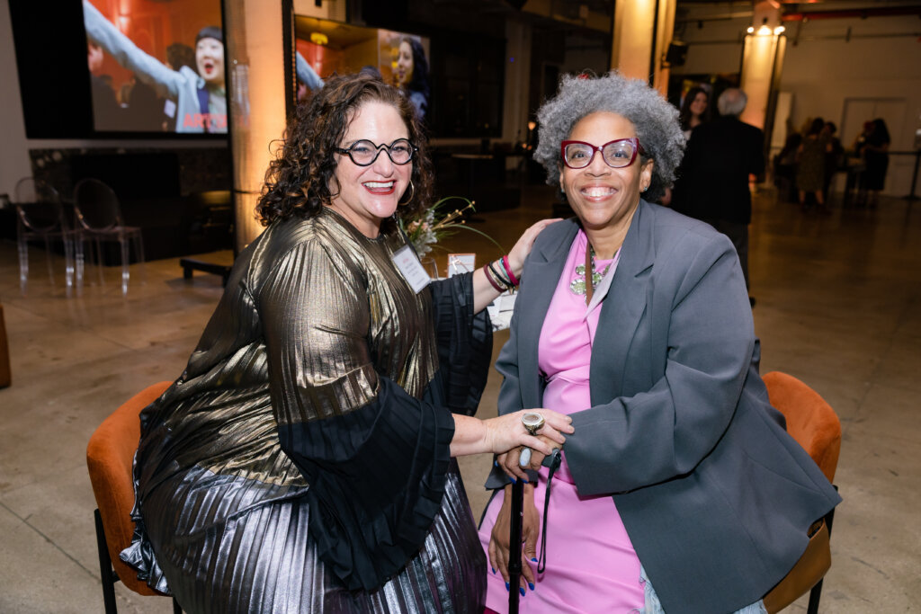 Two women smiling and holding hands.