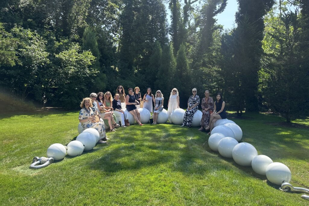 A group of women pose around a large sculpture of pearls