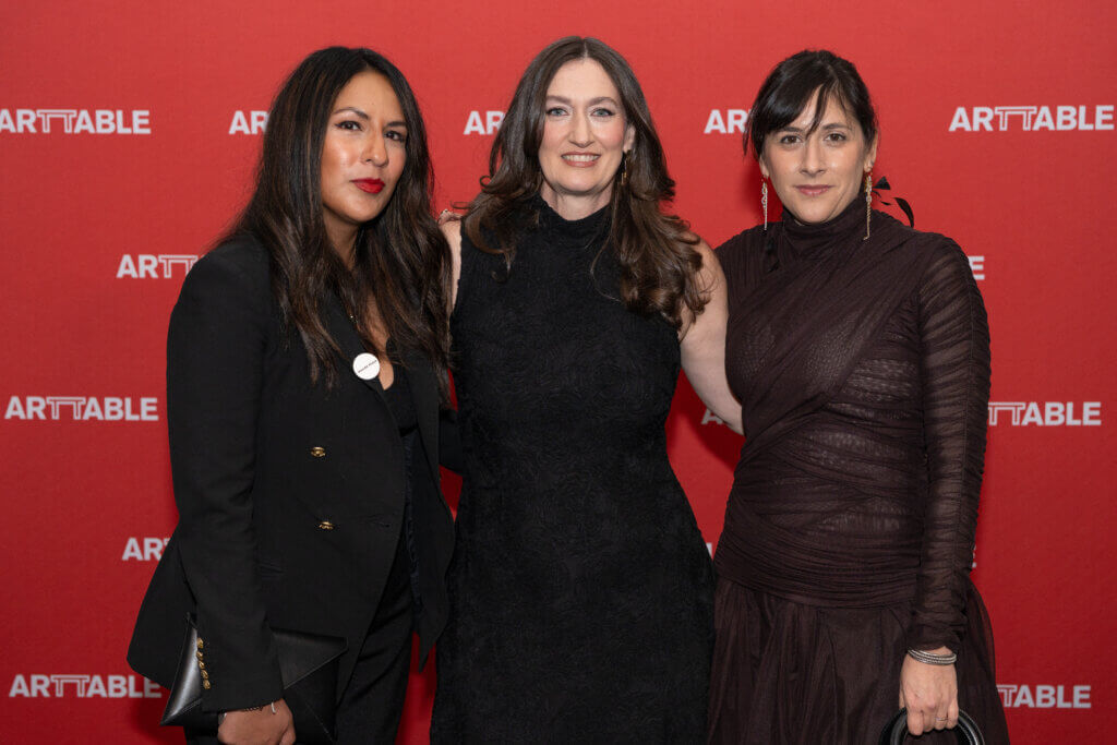 3 women smiling at the camera in front of the ArtTable step and repeat
