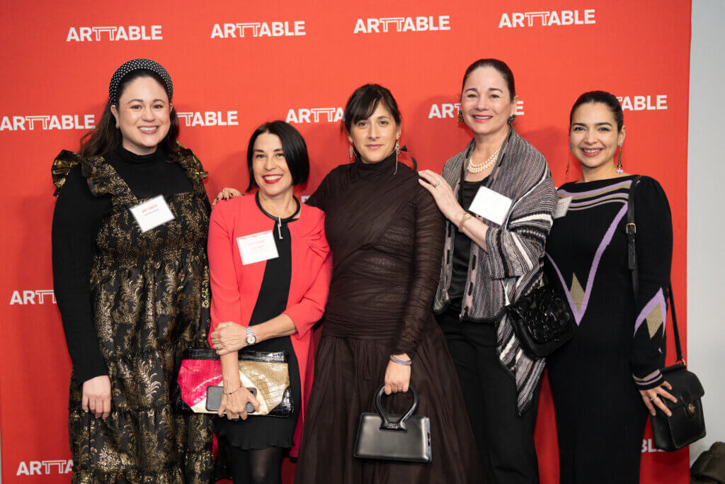 Group of women smiling at the camera in front of the ArtTable logo
