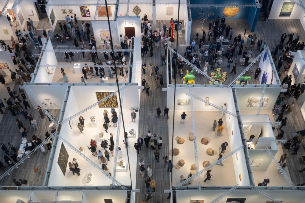 Arial view image of Frieze art fair at The Armory in 2025. It shows gallery cubicles of different sizes with hallways in between. The entire image is covered with people in each of the spaces.
