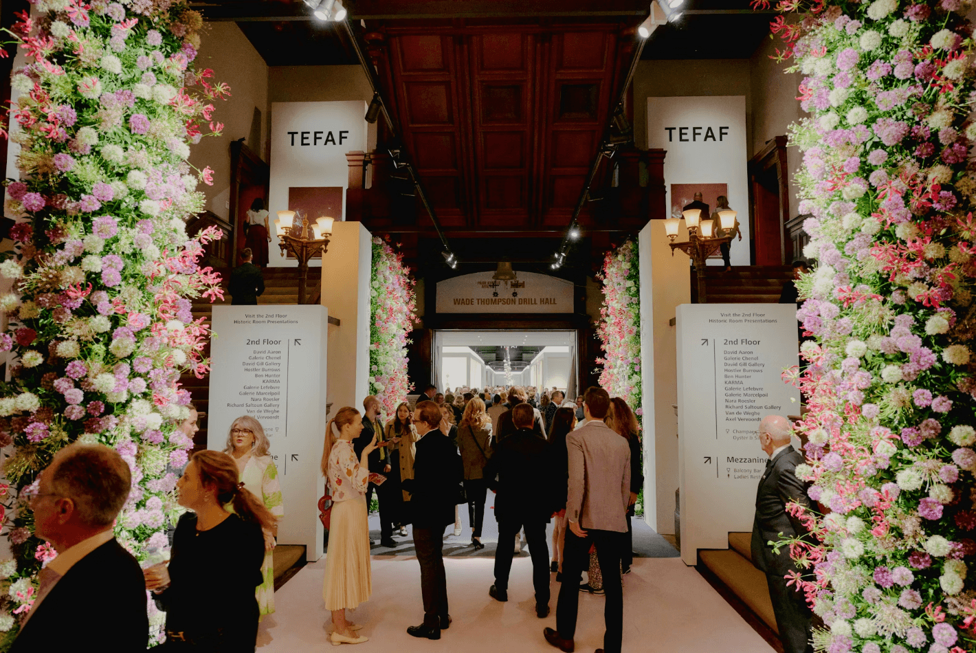Entrance to TEFAF fair in 2025 with columns of flowers and people walking in